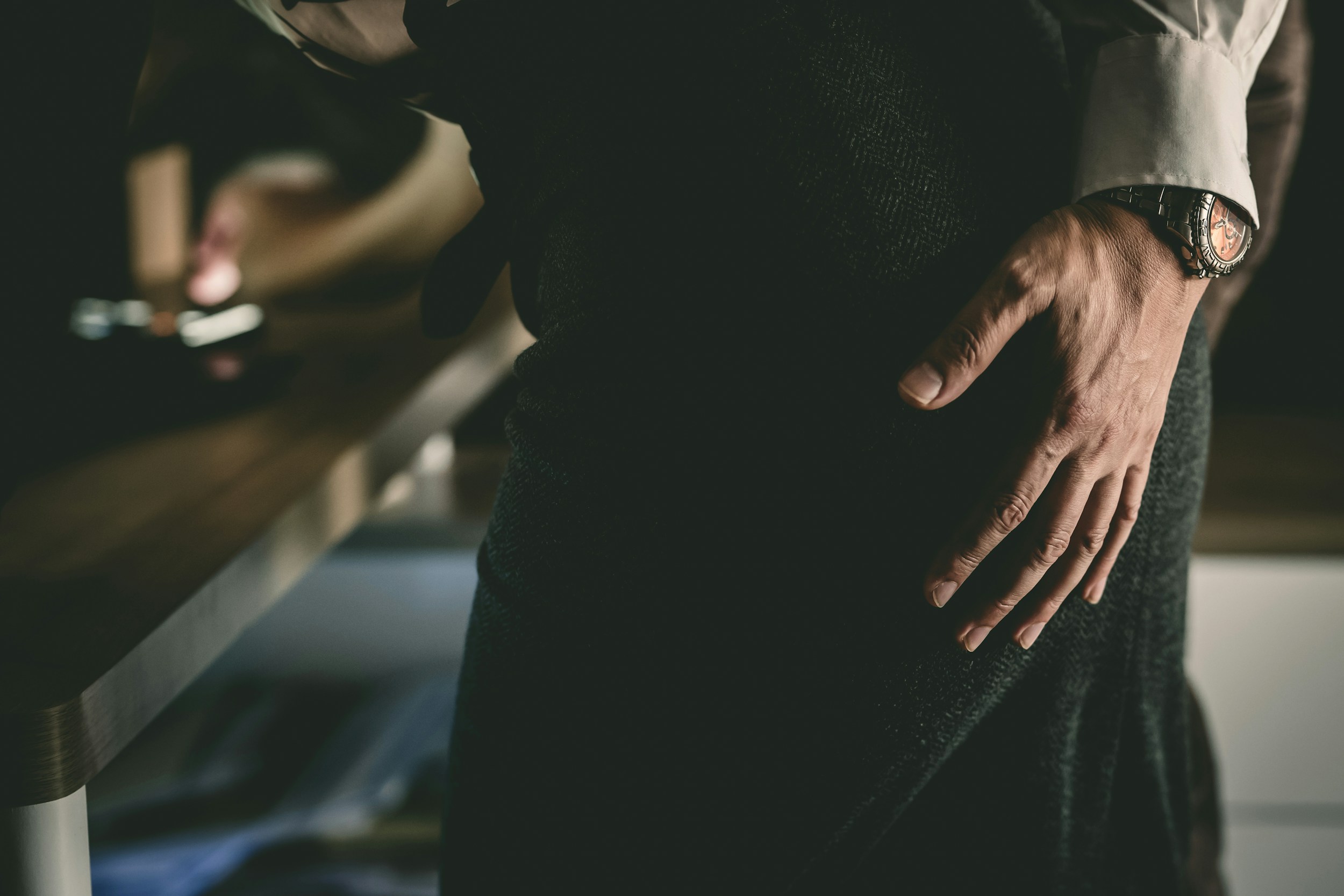 Person holding their stomach in discomfort while sitting at a desk looking stressed