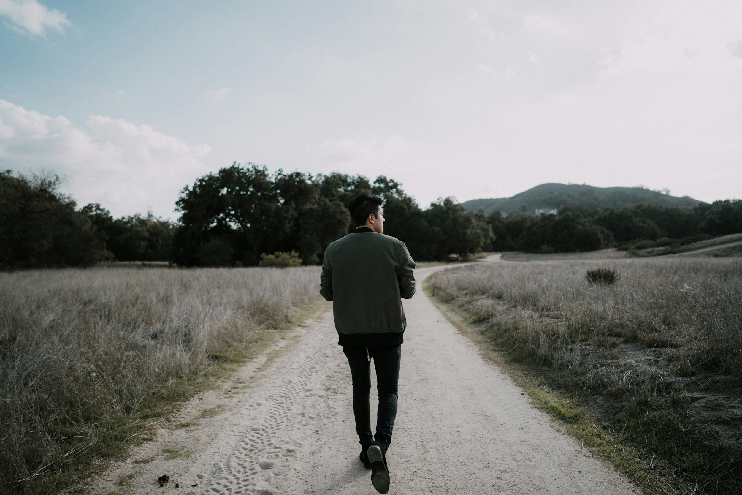 Person jogging outdoors on a sunny path surrounded by trees