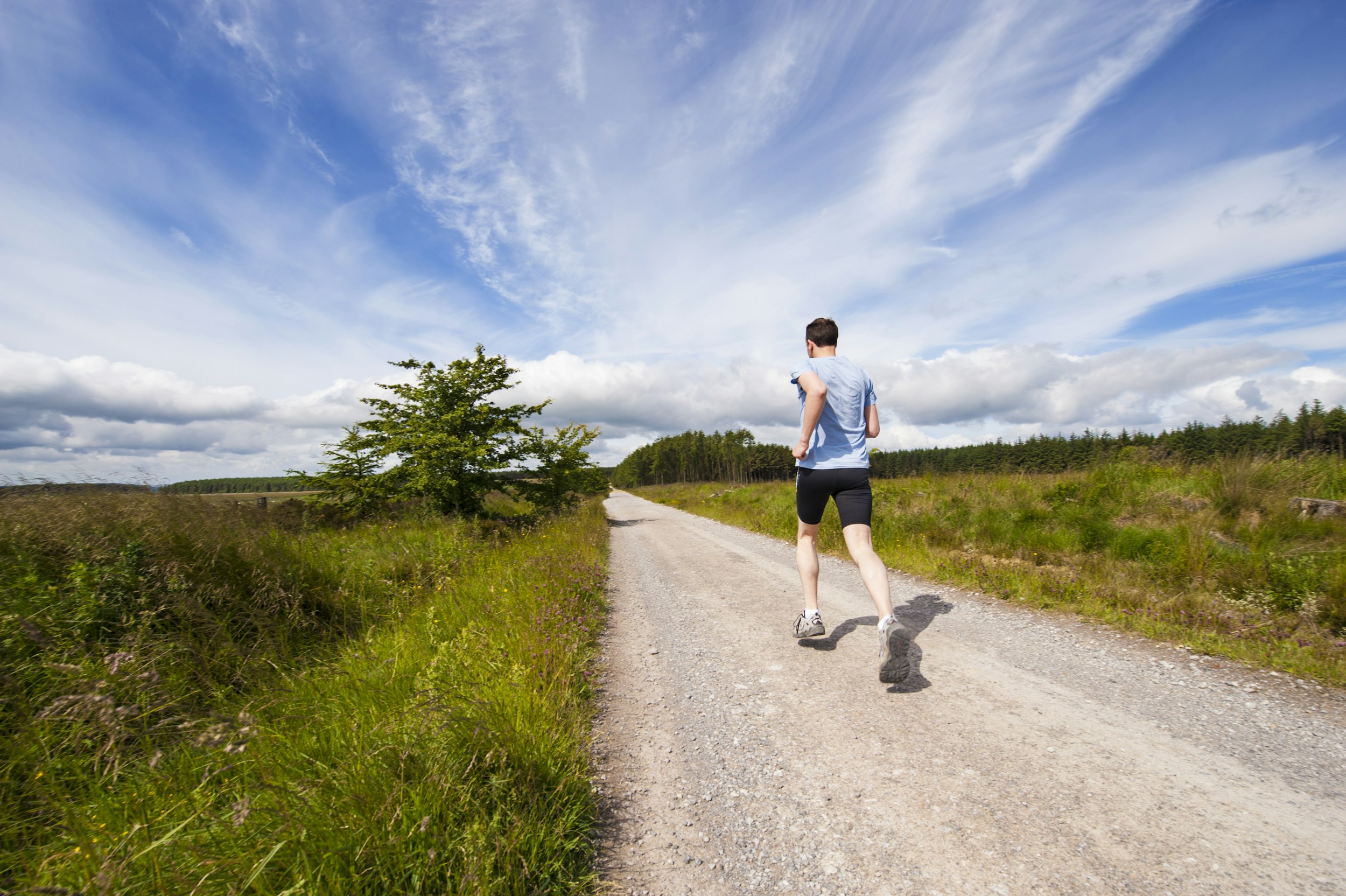 Runner on a trail holding their stomach in discomfort