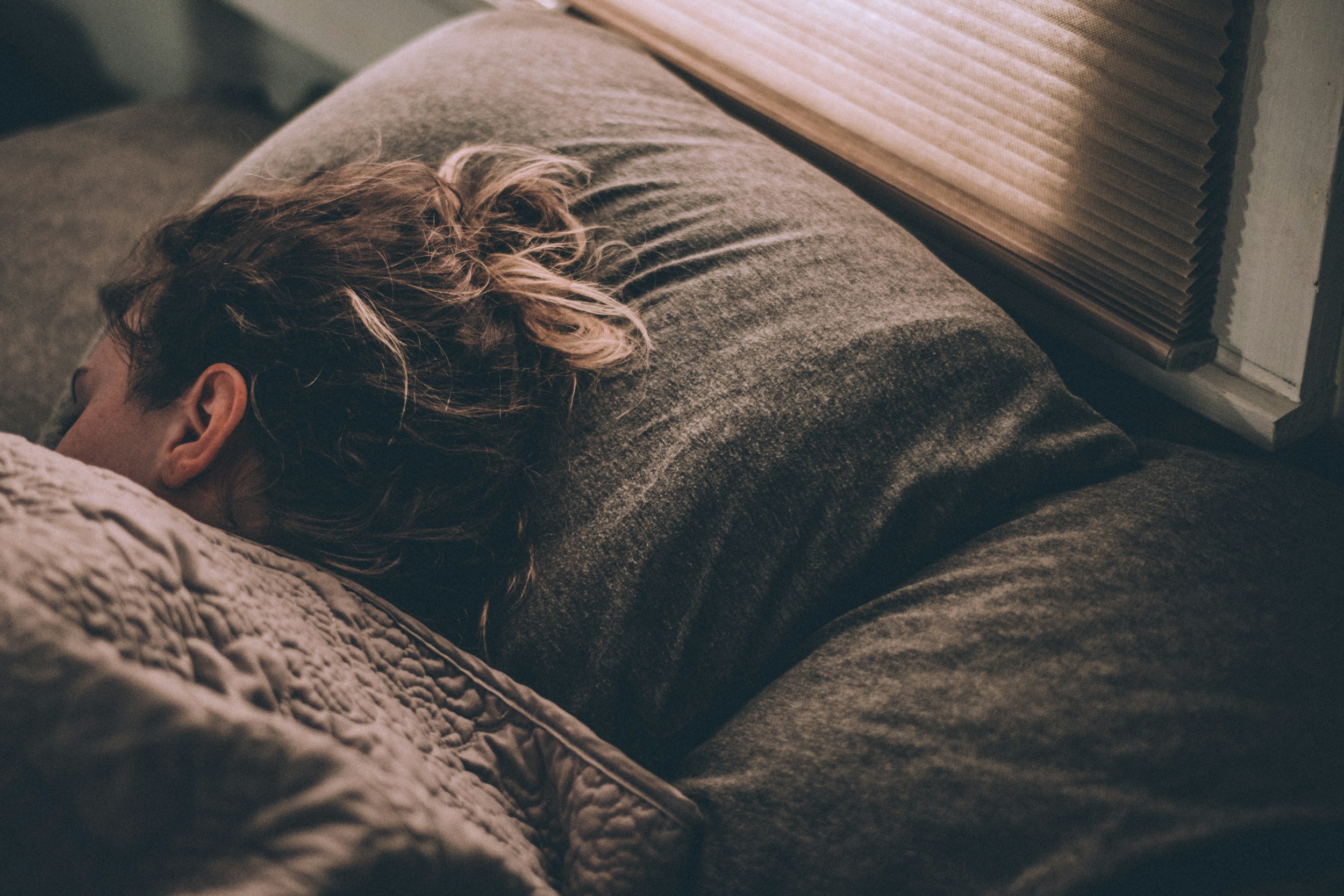 Person sleeping on their side in a comfortable bed with soft lighting